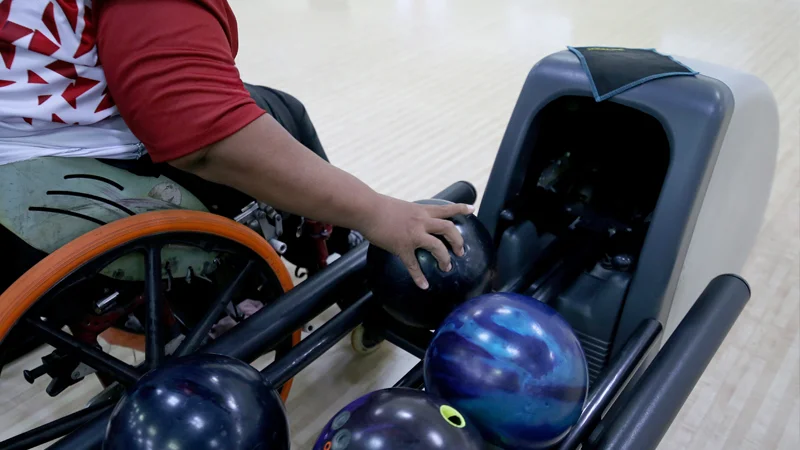 person in a wheelchair reaching for a bowling ball